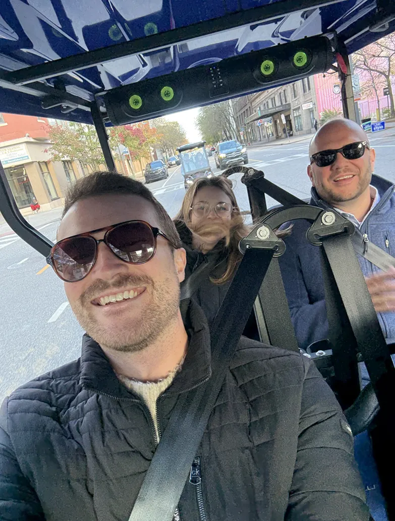 Riders smiling on a Golf Cart Girl-CLE cart in Cleveland.