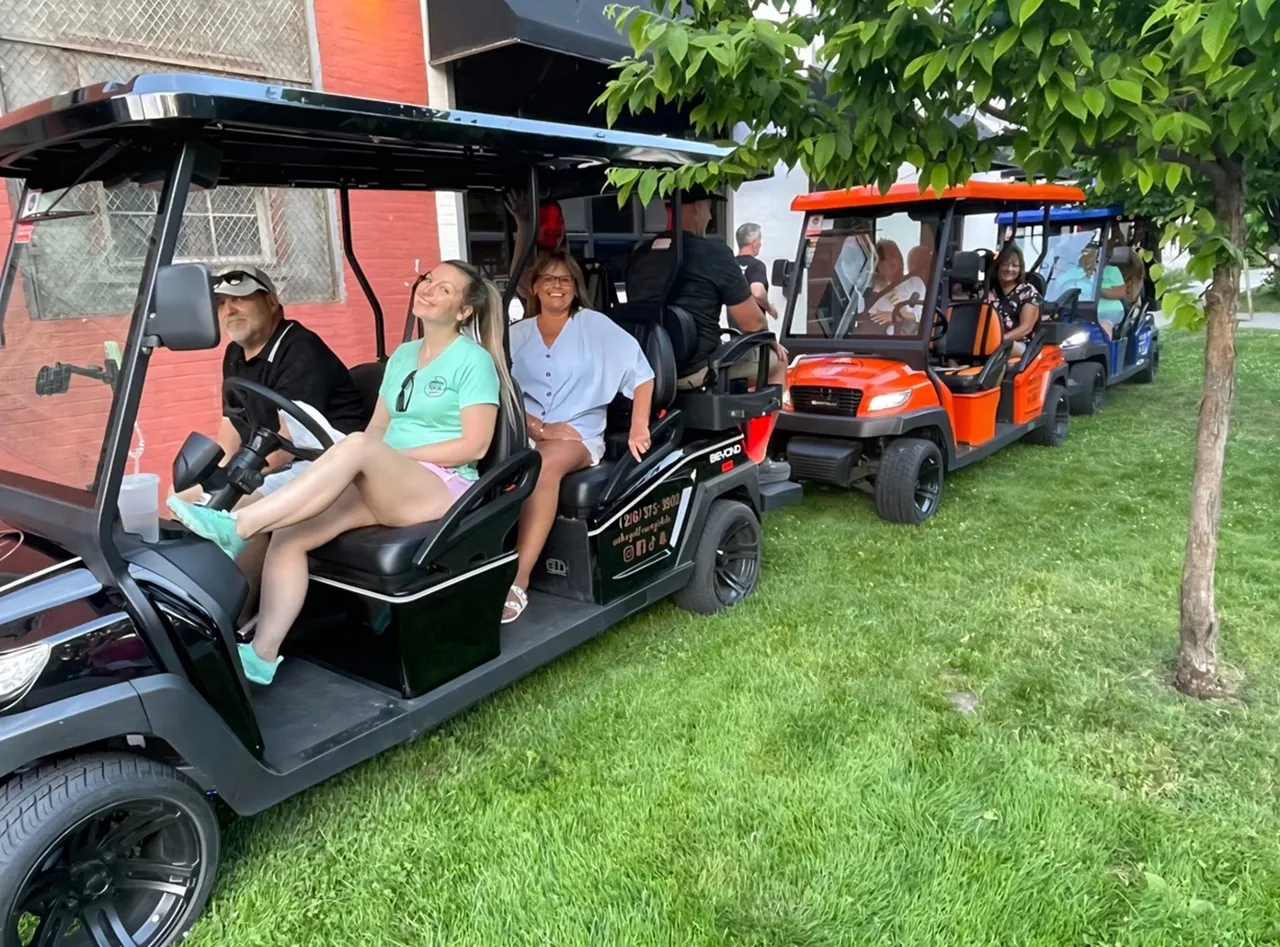 Riders posing with a Golf Cart Girl-CLE cart at a Cleveland stop.